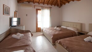 A hotel room with two beds, a television, and a wooden ceiling. - Pension Eliza (Skiathos)
