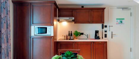 A compact kitchen with wooden cabinets, a microwave, a coffee maker, and a sink.