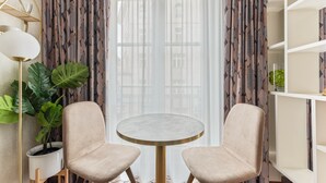 A room with a round table and two chairs, a potted plant, and a bookshelf. - AdvaStay by KING's (Munich)