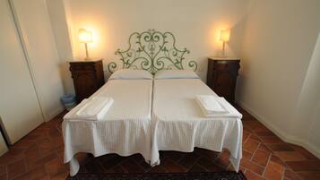 Un letto matrimoniale con testiera in metallo verde, due comodini con lampade e una coperta a quadri.