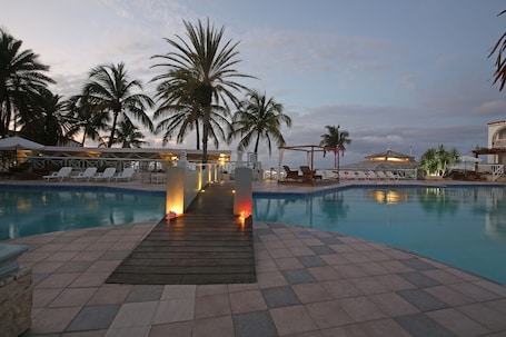 Una piscina al aire libre, sombrillas, sillones reclinables de piscina