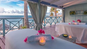 A seaside spa with two massage tables, a wooden deck, and a view of the ocean. - Ocean Point Beach Resort & Spa - Adults Only (St. John's)