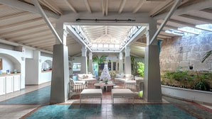 A spacious lobby with a high ceiling, white pillars, and a central seating area with a Christmas tree. - Ocean Point Beach Resort & Spa - Adults Only (St. John's)