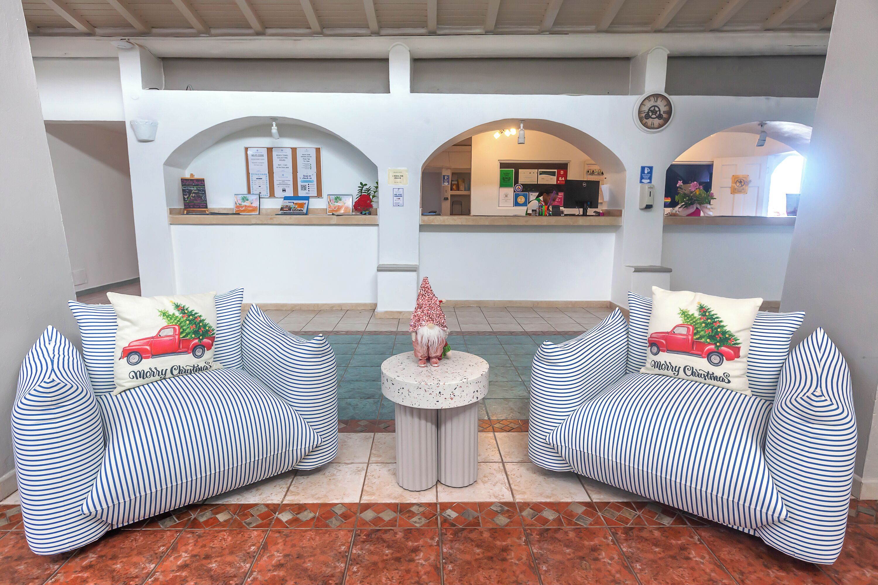 A reception area with two striped sofas, a small round table, and a Christmas tree decoration.