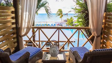 A wooden deck with wicker furniture and a view of the ocean.