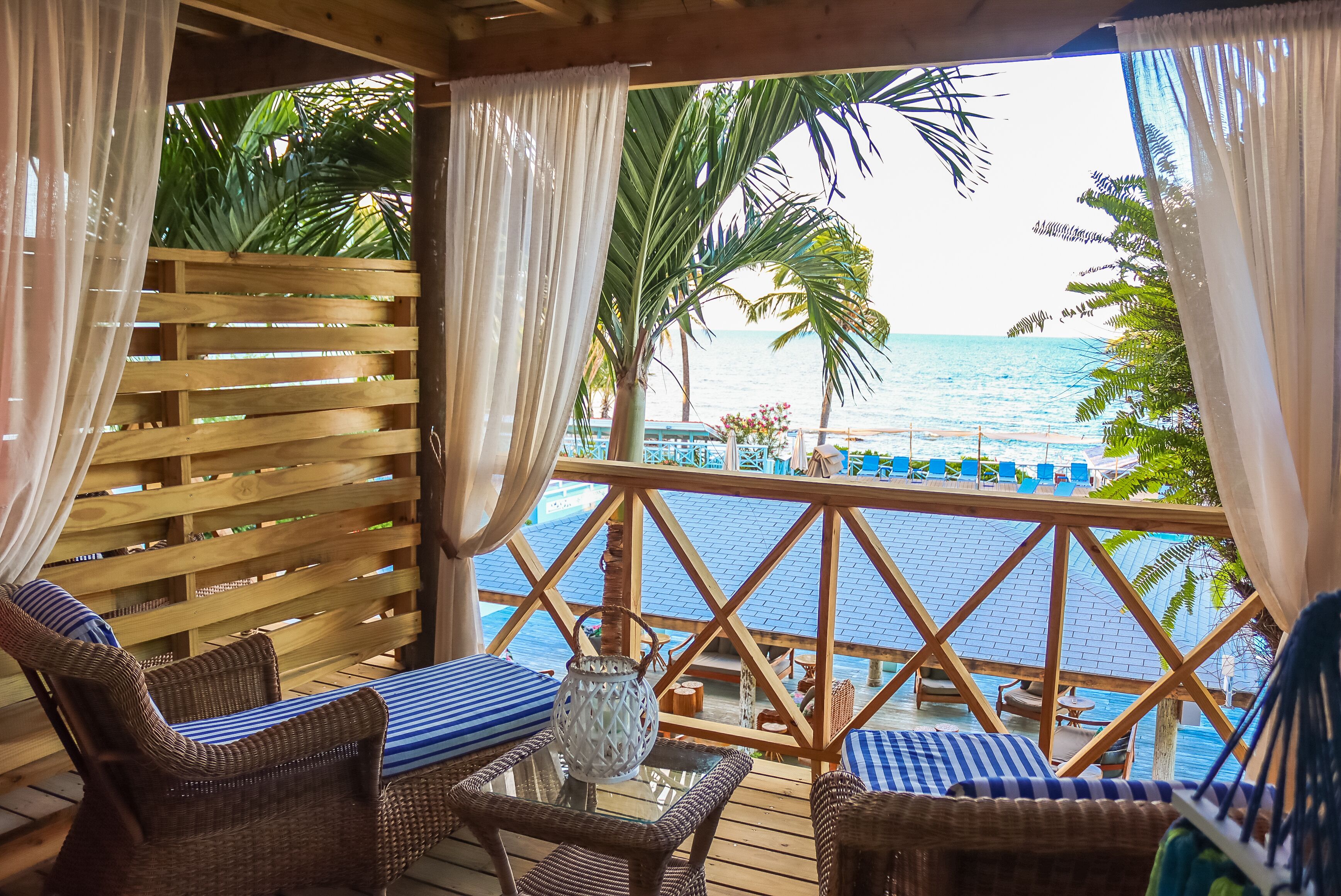 A wooden deck with wicker furniture and a view of the ocean.