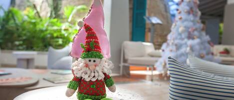 A gnome figurine on a table, a white Christmas tree, and a modern interior with a stone wall and large windows.