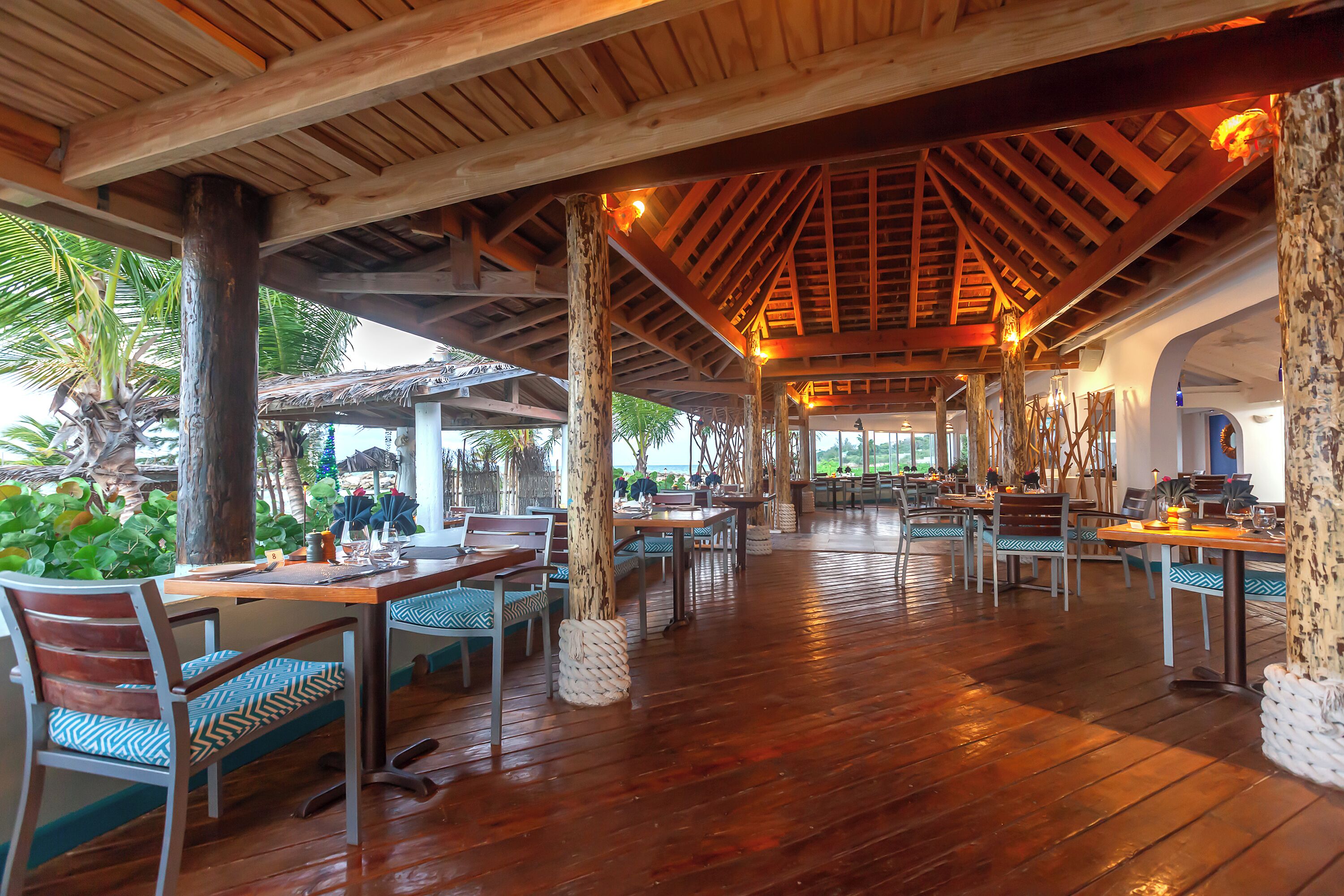 Un restaurante al aire libre con vigas de madera y mesas.