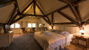 Un dormitorio con una cama grande, vigas de madera, un escritorio y una silla.