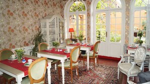 Comedor con mantel rojo, sillas blancas y una lámpara de araña.