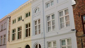 Un edificio de varios pisos con fachada blanca, múltiples ventanas y una puerta negra.