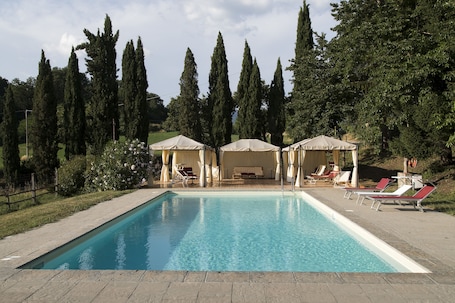 Una piscina al aire libre, sombrillas, sillones reclinables de piscina