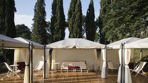 A wooden deck with a white canopy seating area, including a sofa and lounge chairs. - Agriturismo La Topaia (Borgo San Lorenzo)