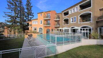 Ein Poolbereich mit Glasveranda, umgeben von einer Holzterrasse und weißen Geländern.