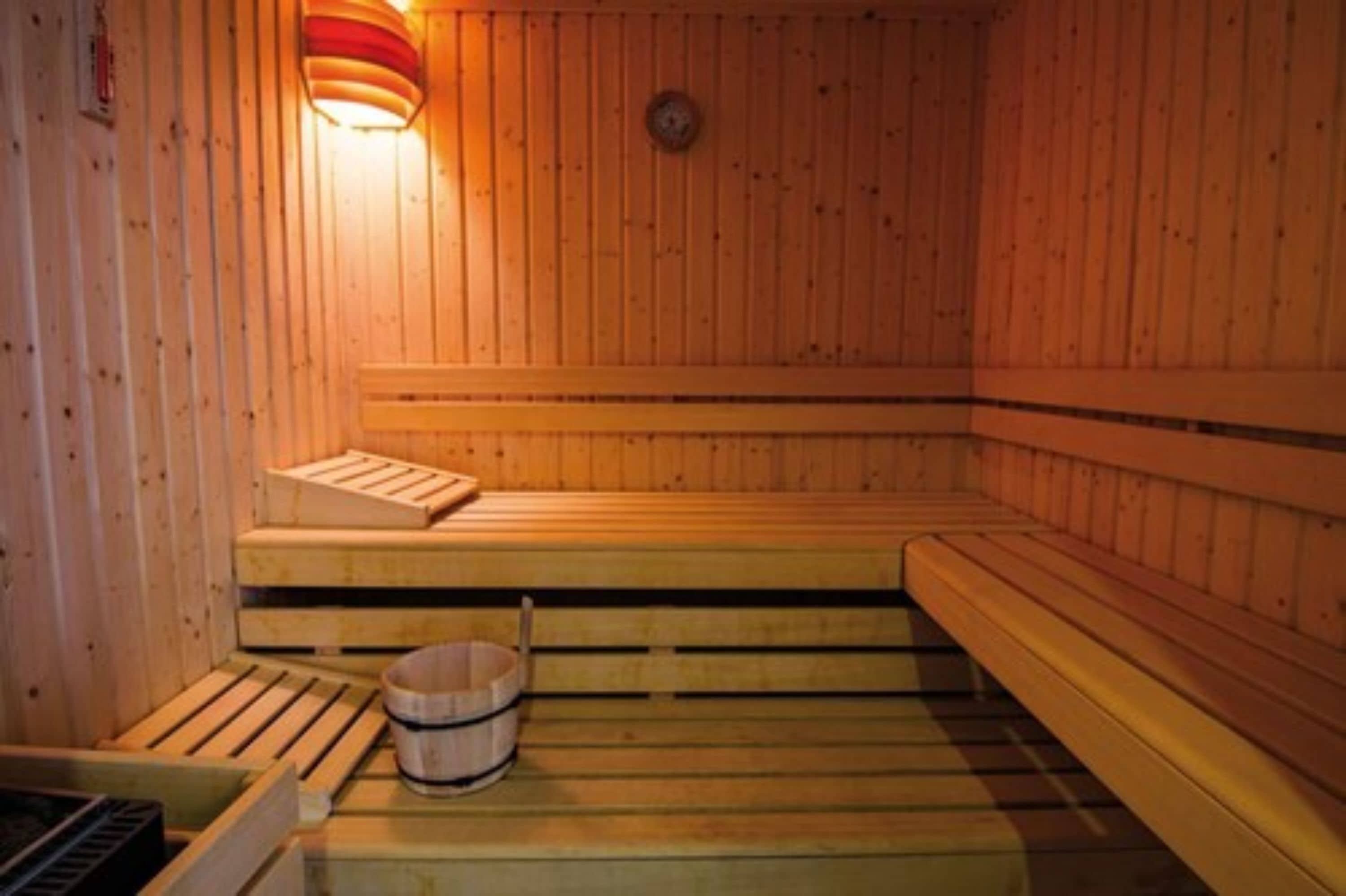A wooden sauna with benches and a bucket.