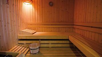 Een houten sauna met banken en een emmer.