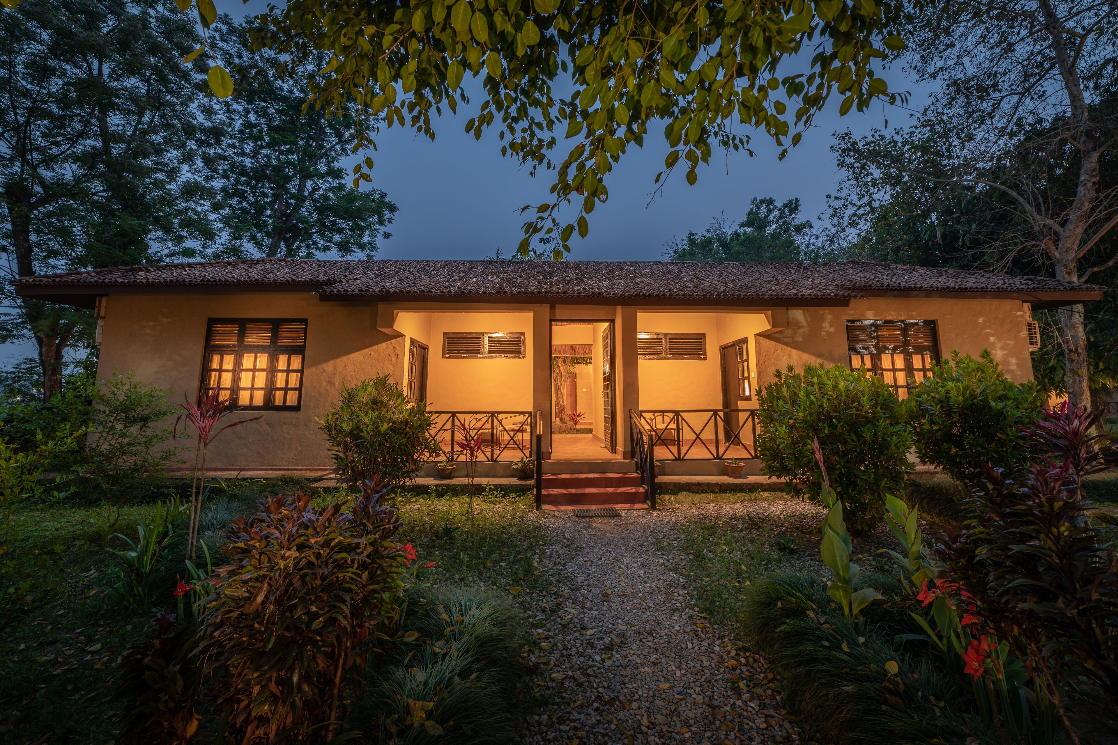 A two-story house with a tiled roof, a front porch, and a gravel pathway leading to the entrance.