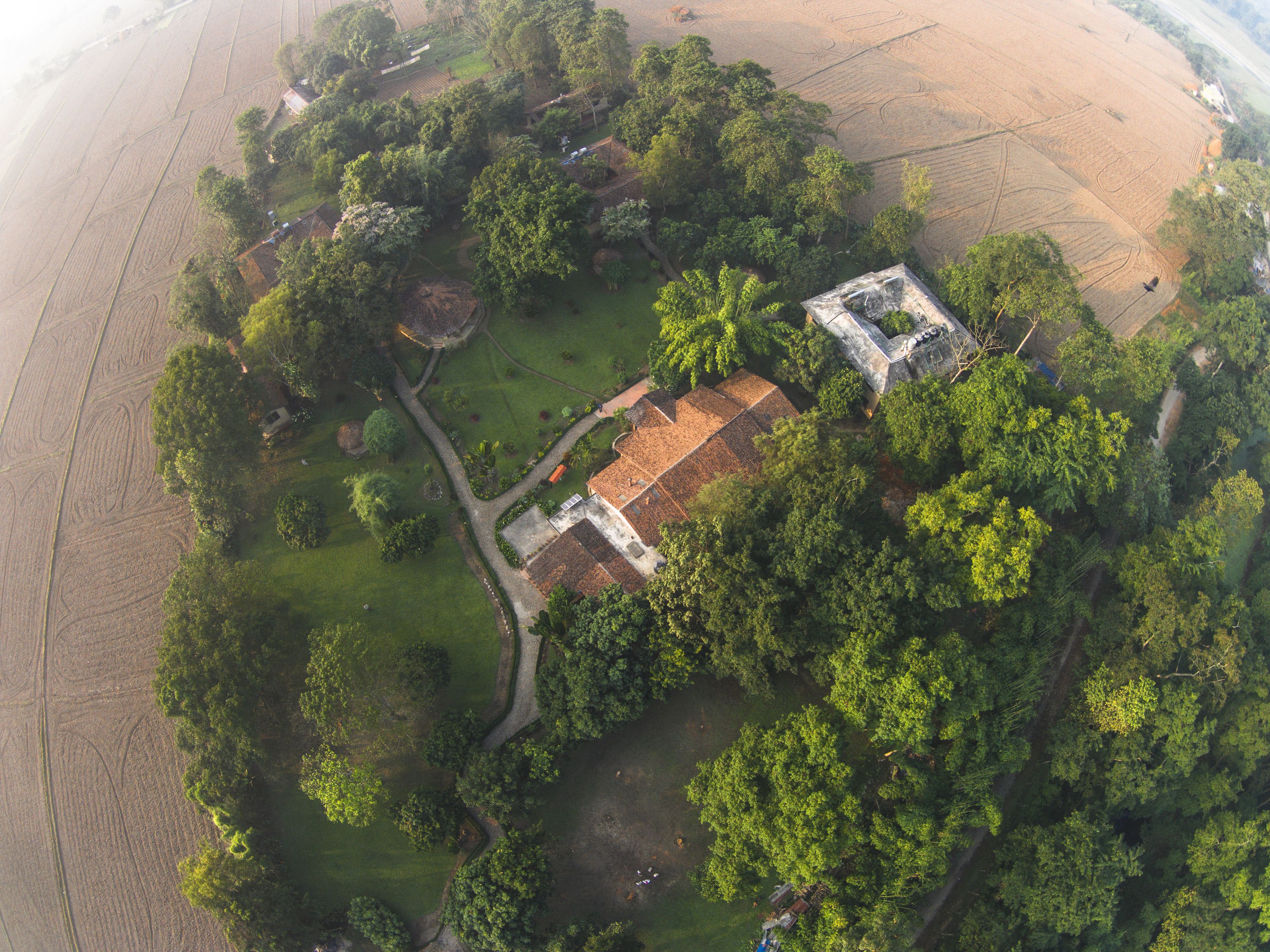 Vista aérea de una propiedad con un edificio central rodeado de exuberante vegetación y campos.