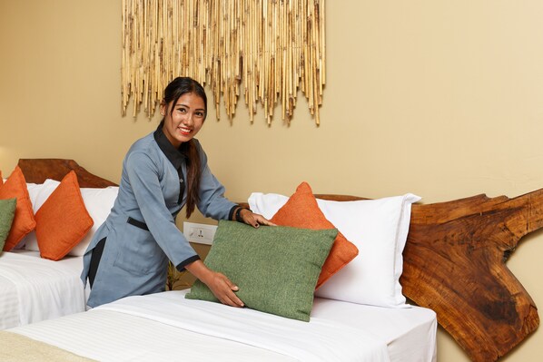 Una habitación de hotel con cama, almohadas y cabecero de madera.
