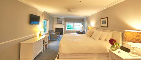 A bedroom with a bed, desk, chair, and a fireplace.