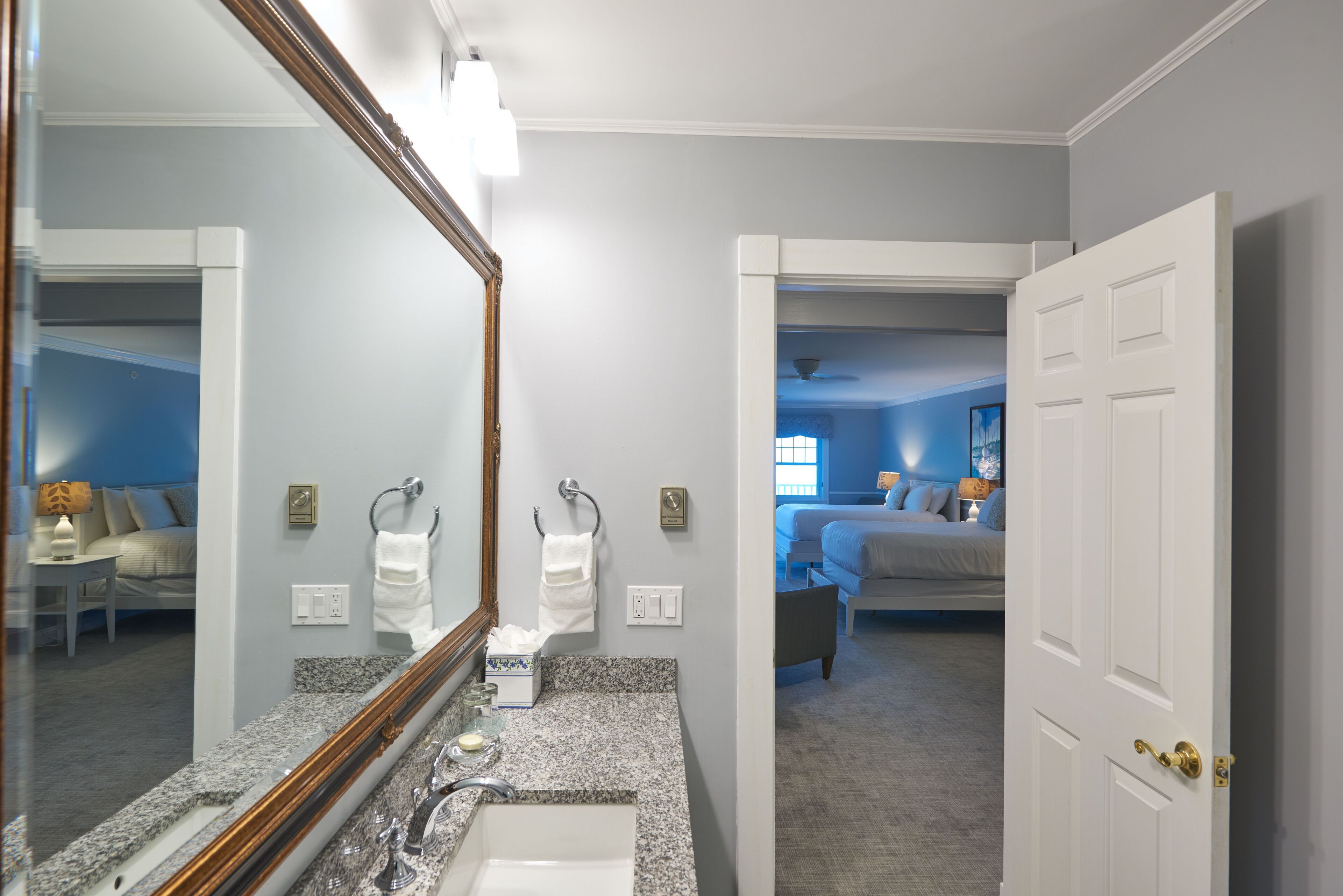 A bathroom with a large mirror, granite countertop, and a sink.