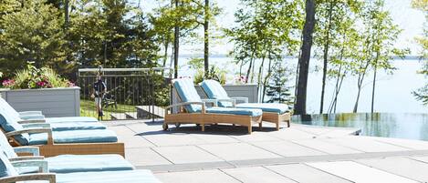 Un espace aménagé au bord de la piscine, avec des fauteuils de relaxation en osier et un petit coin salon abrité.