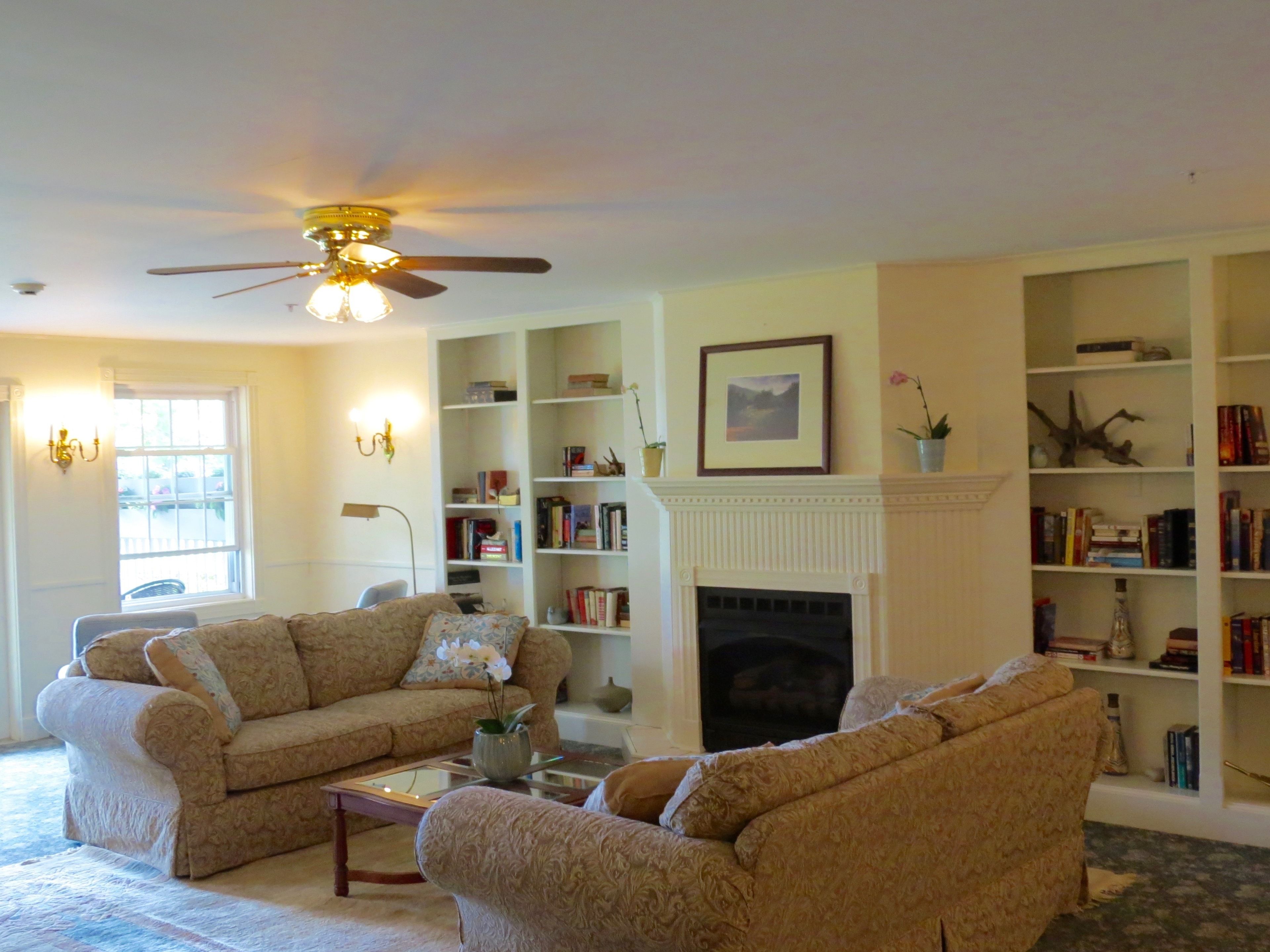 A living room with two sofas, a fireplace, and bookshelves.