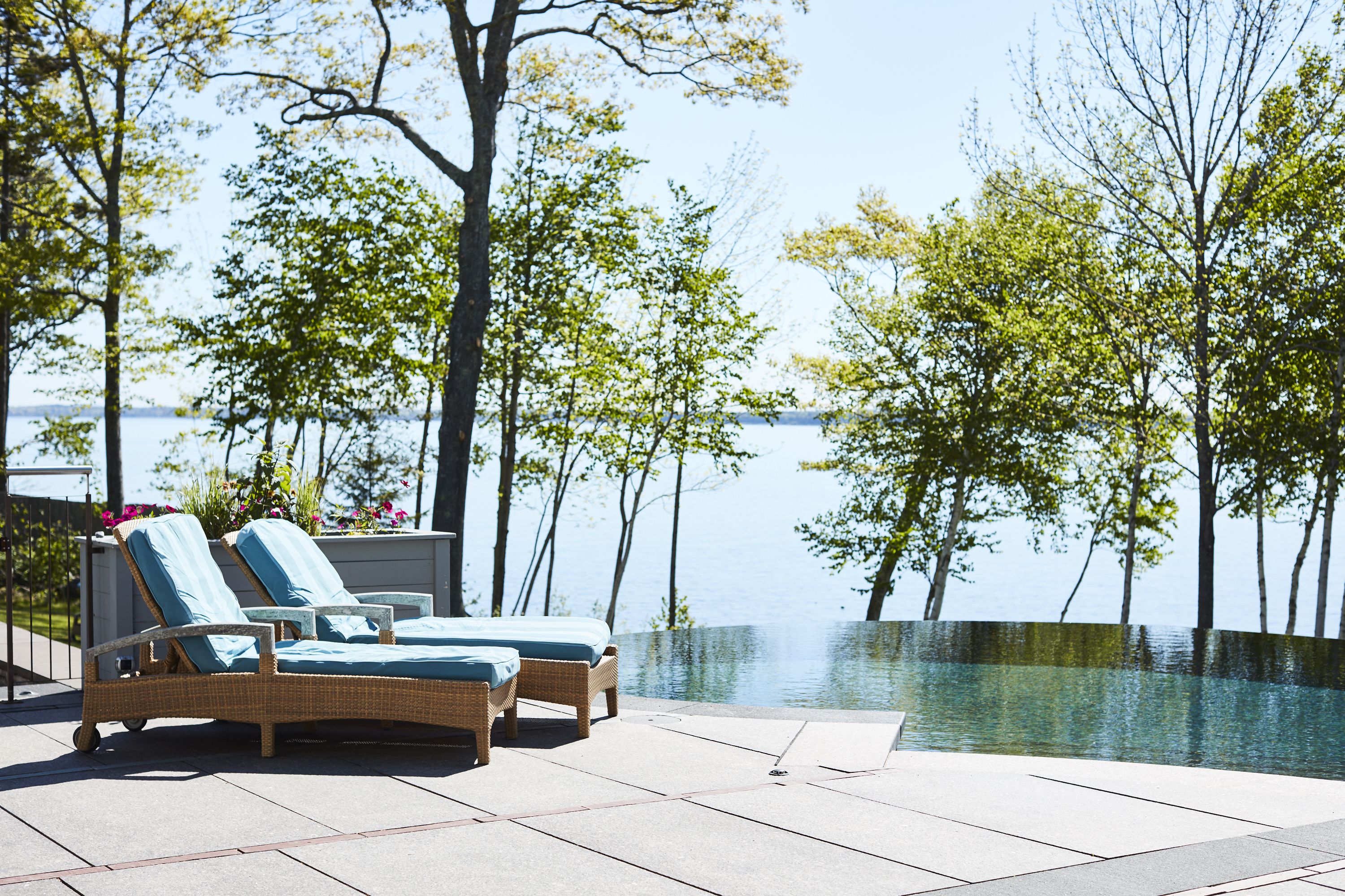 A poolside area with two wicker lounge chairs and a view of the water.