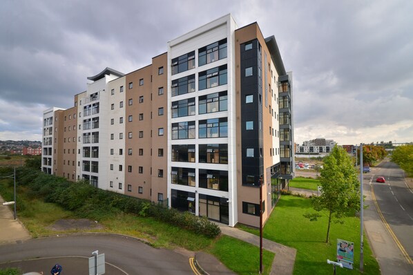 A multi-story residential building with a modern design, featuring a mix of window styles and a flat roof.