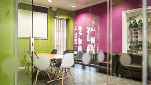 Un salón de conferencias con separador de vidrio, una pizarra y disposición de asientos.