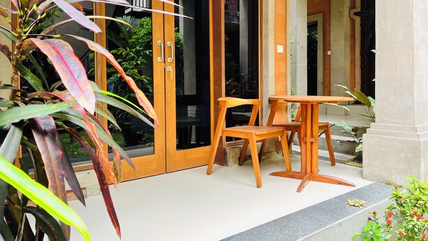 Une porte en bois avec des panneaux de verre, une petite table en bois et des chaises devant un bâtiment.