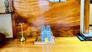 Un bureau en bois sur lequel se trouve un plateau contenant deux bouteilles d’eau et une télécommande.