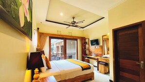 Une chambre d’hôtel avec un lit, un bureau, une télévision et un balcon.