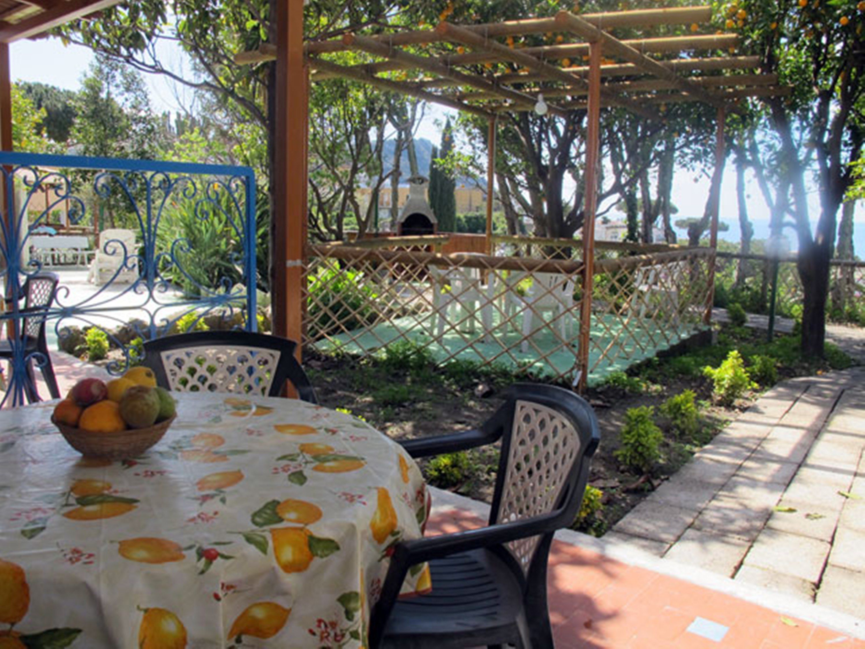 A covered outdoor seating area with a table set for two, surrounded by chairs.
