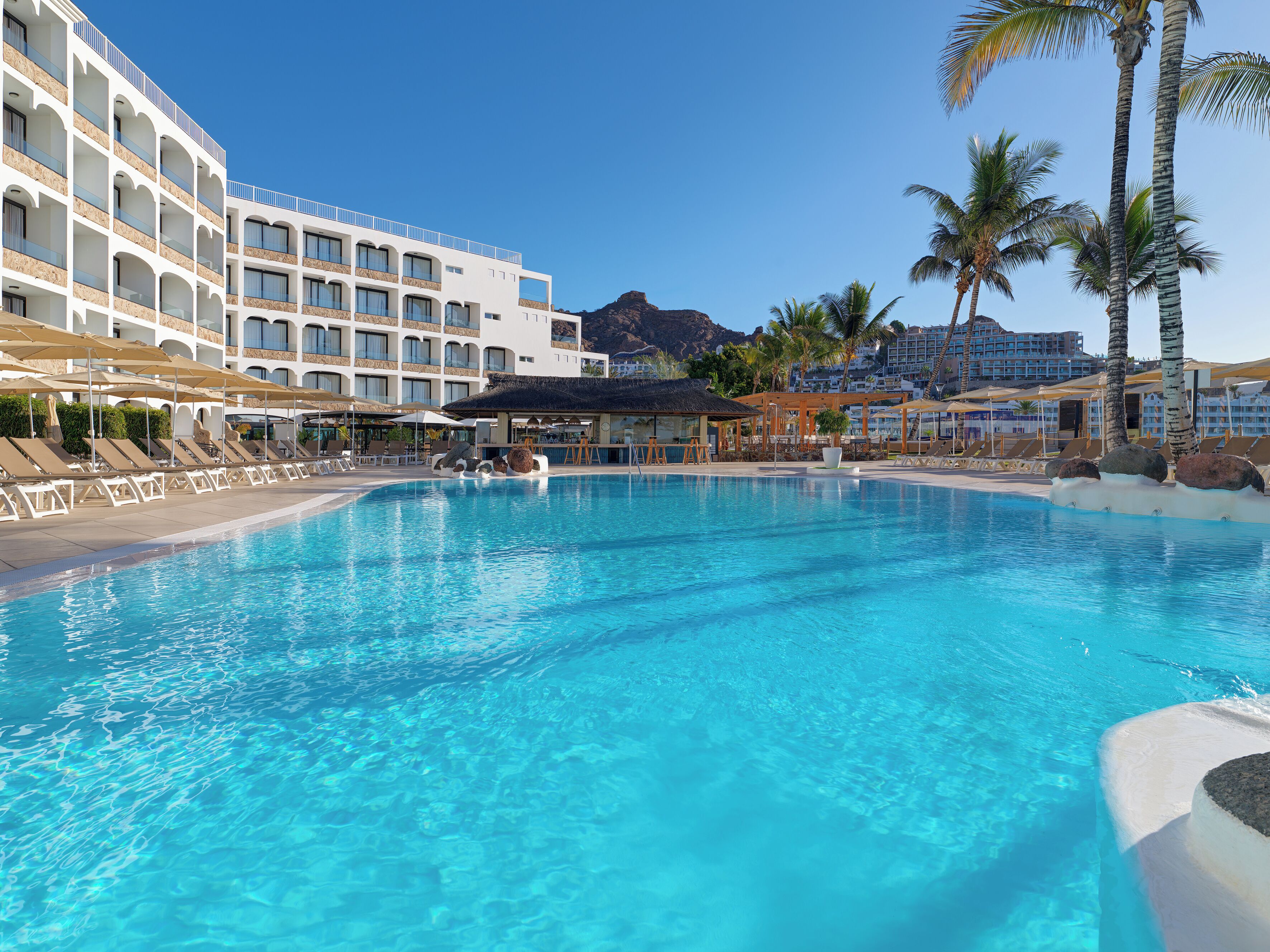 Een buitenzwembad, parasols voor strand/zwembad