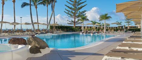 Una piscina al aire libre, sombrillas, tumbonas