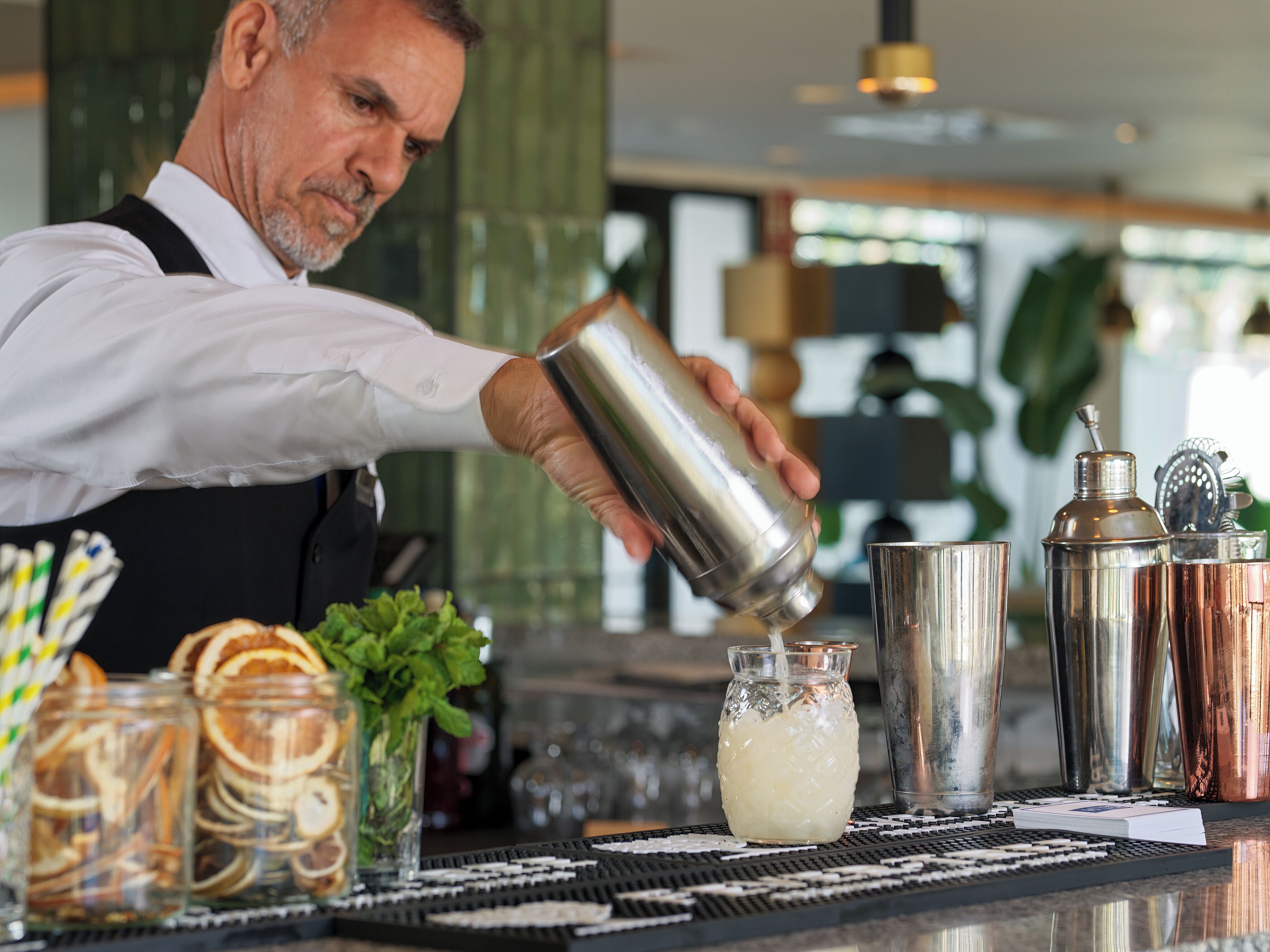 A bartender pouring a drink into a glass.