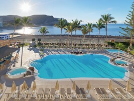 Una piscina al aire libre, sombrillas, tumbonas