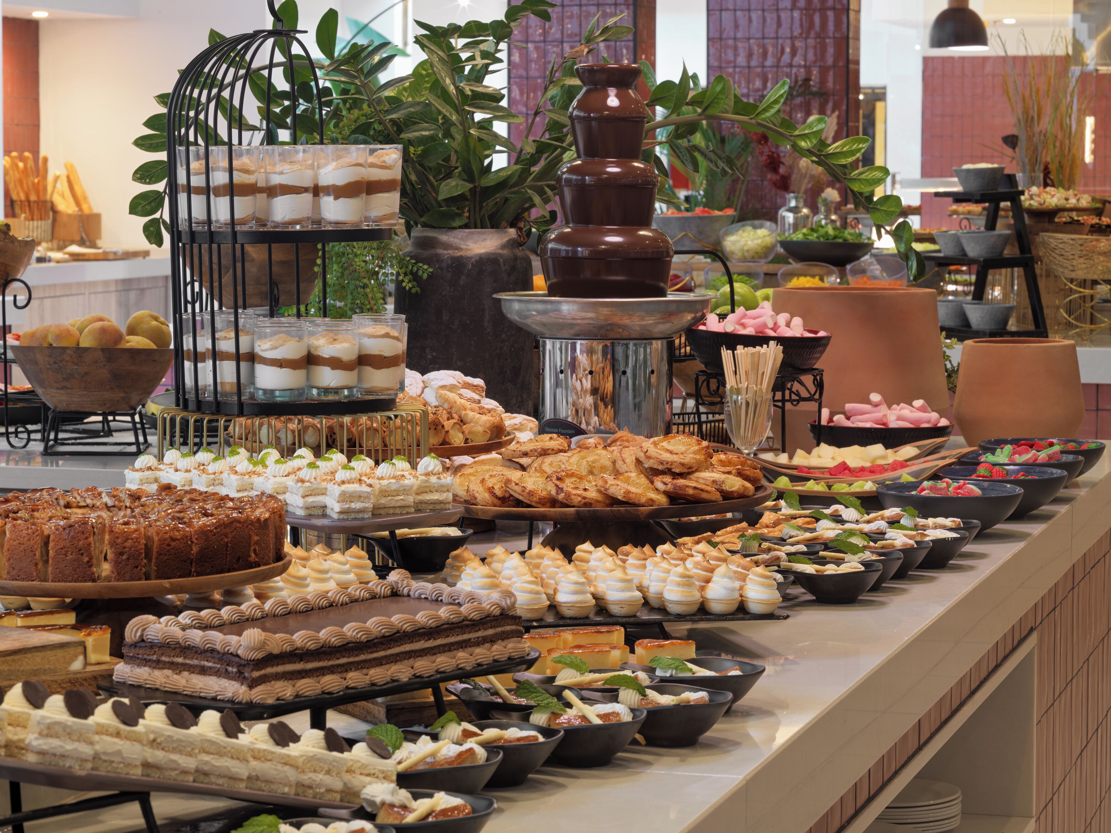 A buffet with various desserts and pastries, including cakes, pies, and fruit bowls.