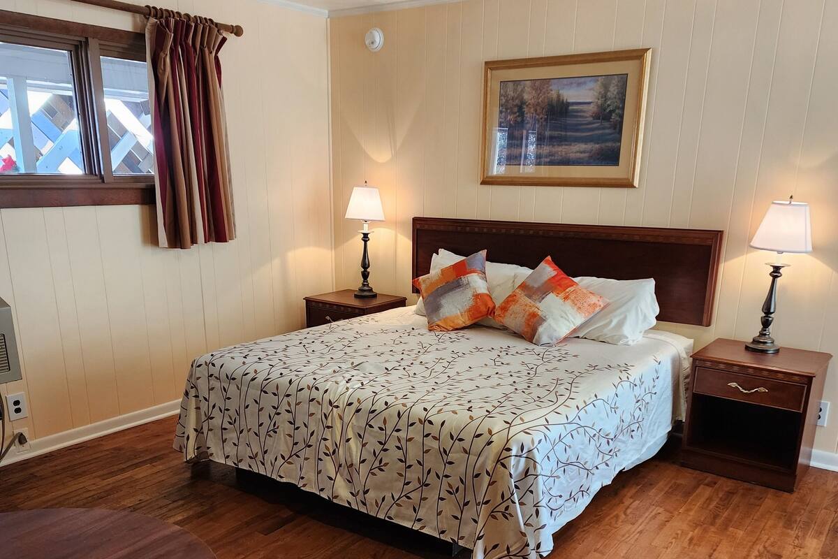 A neatly arranged hotel room with a bed, two bedside tables, a round wooden table, and a chair.