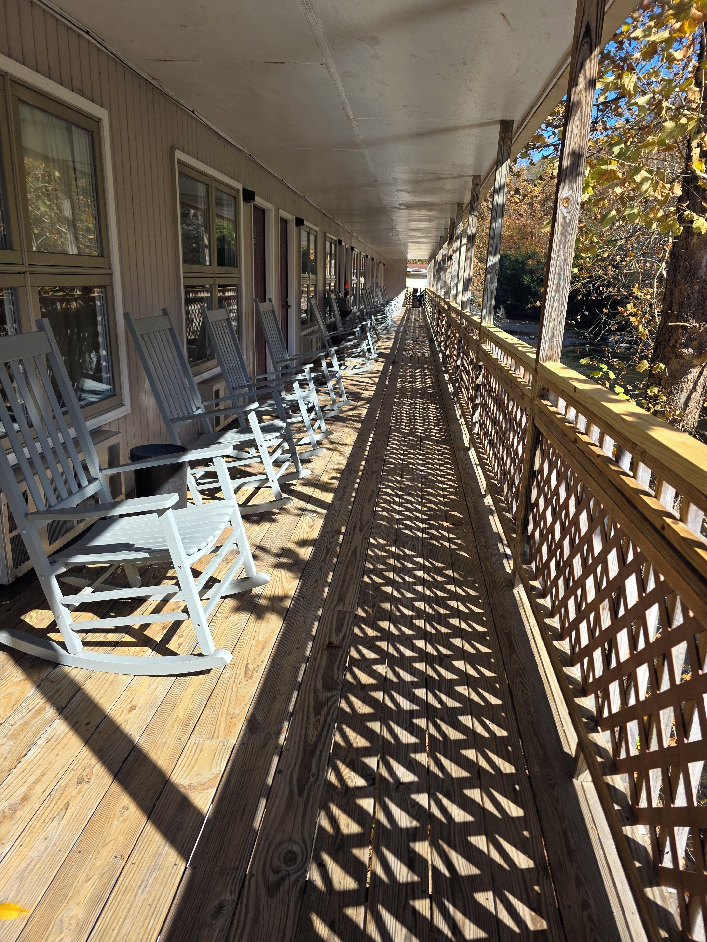 A covered outdoor seating area with wooden flooring and a lattice railing.