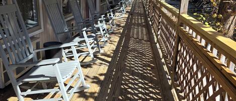 A covered outdoor seating area with wooden flooring and a lattice railing.