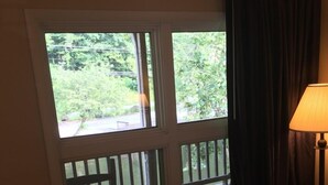 A room with a large window, a round wooden table, and a patterned sofa. - Drama Inn (Cherokee)