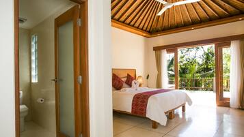 Ein Schlafzimmer mit Bett, Deckenventilator und Blick ins Freie.