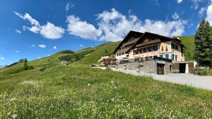 A mountain lodge with a stone facade, multiple balconies, and a restaurant area with outdoor seating. - Hotel Salastrains (St. Moritz)