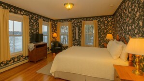 A bedroom with a large bed, a desk, a chair, and a television. - Lakeview Inn (Naples)