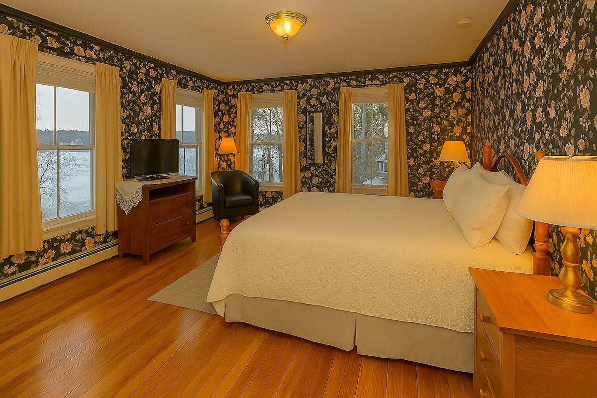 A bedroom with a large bed, a desk, a chair, and a television.