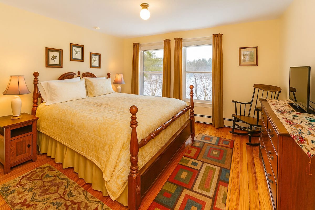A bedroom with a wooden bed, bedside tables, a dresser, a chair, and a window with curtains.