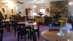 A spacious living room with a fireplace, dining area, and a staircase leading to another level. - Lakeview Inn (Naples)