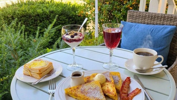 A table with breakfast items, a cup of coffee, and a glass of red drink on a balcony. - Lakeview Inn (Naples)